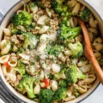 A bowl of ground turkey and broccoli pasta topped with Parmesan and fresh parsley