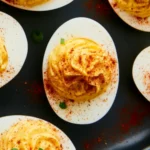 Boiled eggs with paprika arranged on a white serving platter